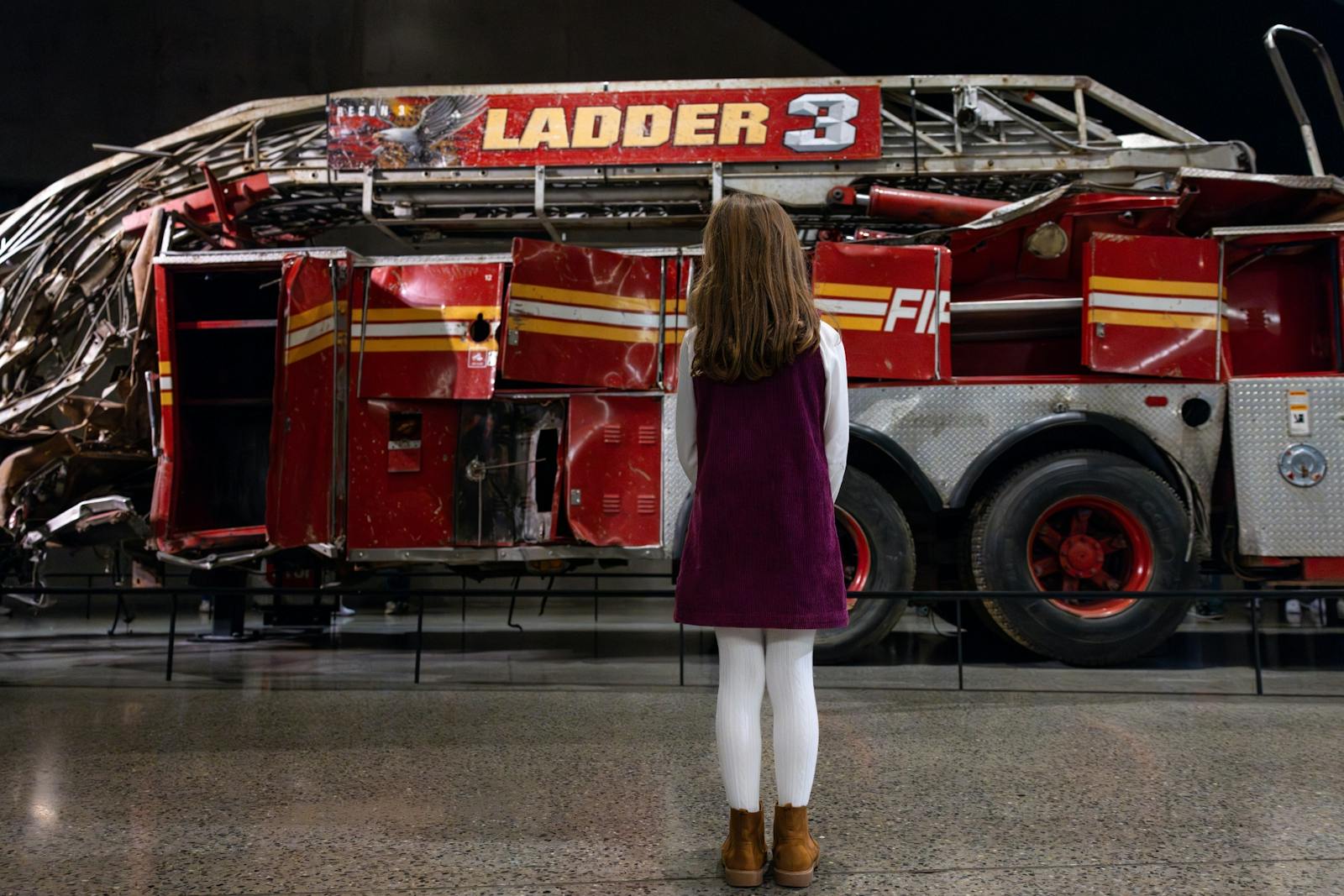 Litet flicka betraktar Ladder 3 vid 9/11 Memorial & Museum